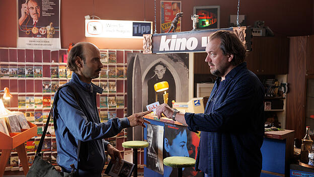 Redakteur Alexander Landmann (Leon Ullrich, links) wittert eine große Geschichte über die angeblichen Heldentaten von Micha Hartung (Charly Hübner), der einst zahlreiche Menschen aus der DDR in die Freiheit geschleust haben soll. Doch Micha zeigt sich davon zunächst alles andere als begeistert.