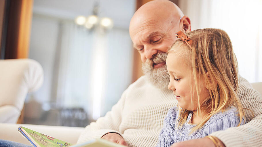 Grandfather, child and family reading on a living room sofa with love and learning support. Happy, home and kid with an
