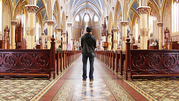 man standing praying in church
