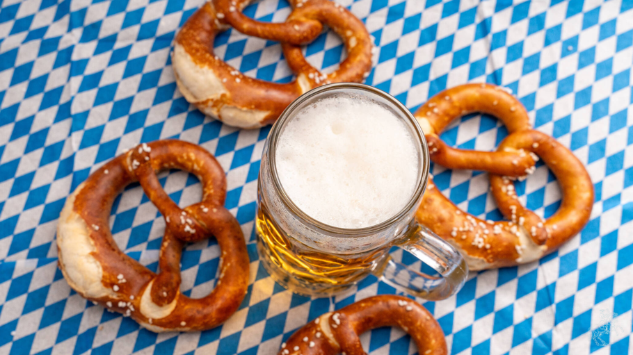 Bavaria, Germany - 25 August 2023: Oktoberfest themed photo, Bavarian flag with beer in Maßkrug and fresh brown pretzels