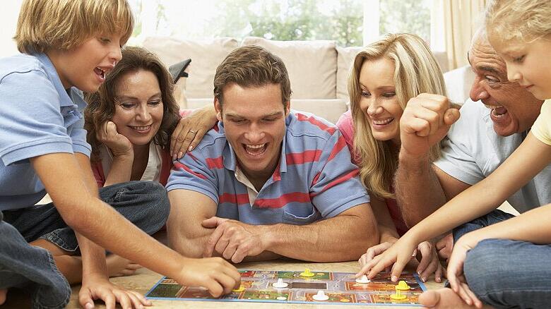 Family Playing Board Game At Home With Grandparents Watching