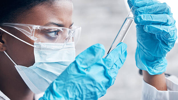 Black woman, scientist and research in lab with test tube for medical innovation and ppe safety for chemistry experiment. African lady, science and pharmaceutical study with liquid sample for vaccine