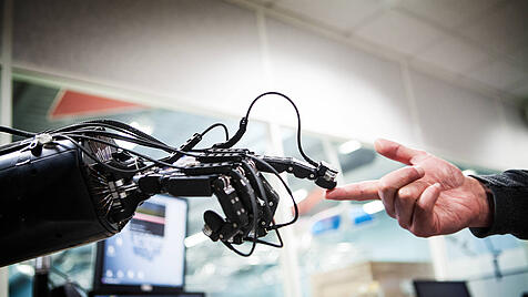 Eine Roboterhand berührt eine Menschenhand. Transhumanisten haben das Ziel, Grenzen der Biologie zu sprengen.