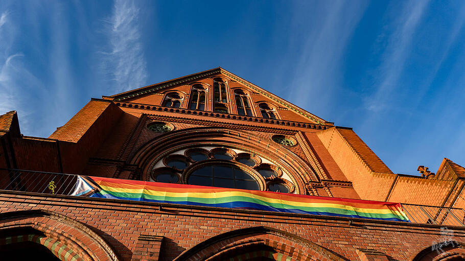 Eine Regenbogen-Fahne an der Fassade der Heilig-Kreuz-Kirche in Berlin
