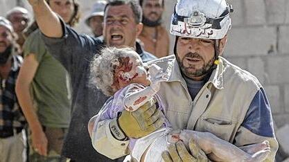A civil defence member carries an injured baby in Marshamsha