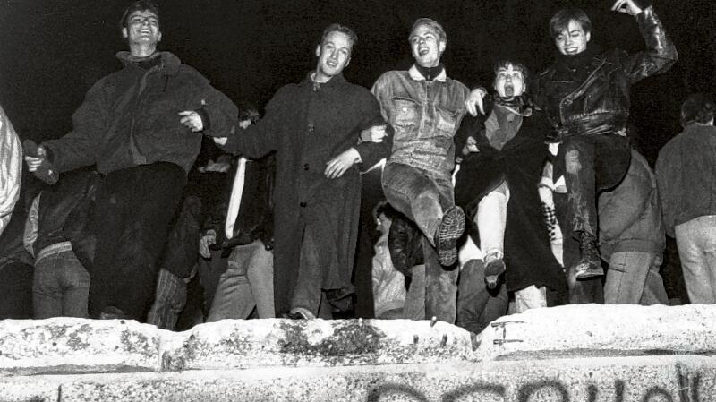 Jugendliche tanzen auf der Berliner Mauer