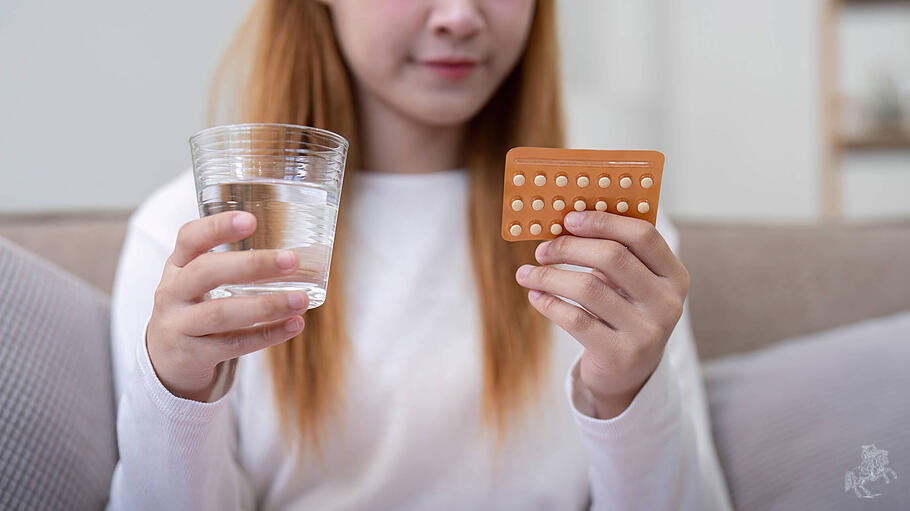 Eine junge Frau mit Verhütungspille und Wasser