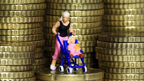 Mutter mit Kleinkind im Kinderwagen steht zwischen Euro Cent Münzen