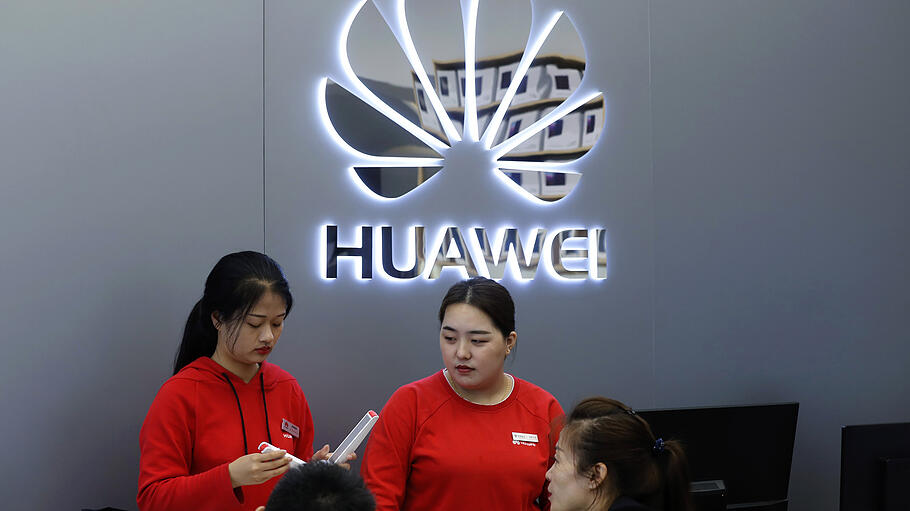 Verkäuferinnen in einem Huawei-Geschäft sprechen mit Kunden