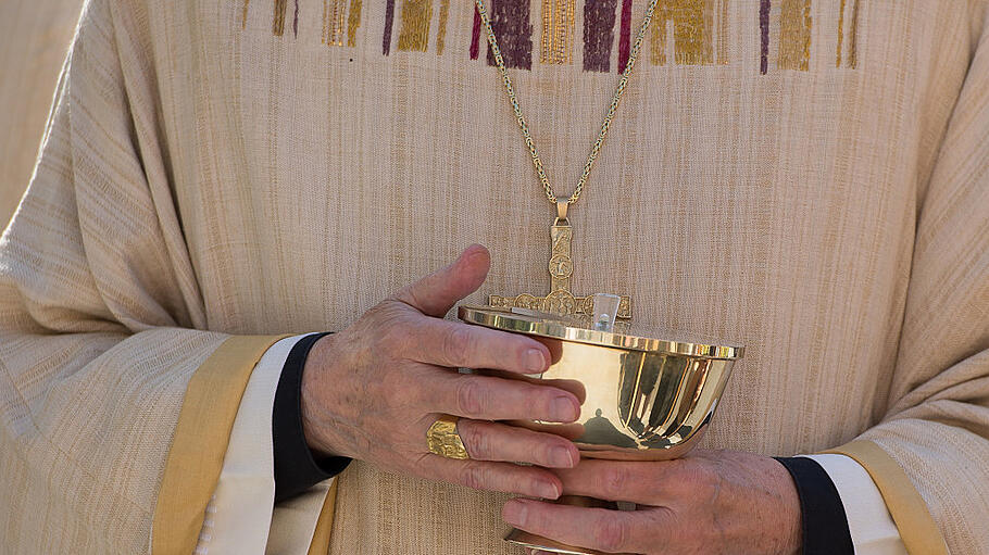 Priester mit einer Hostienschale in den Händen