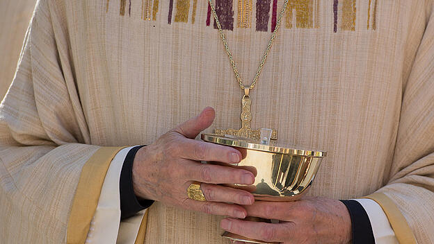Priester mit einer Hostienschale in den Händen