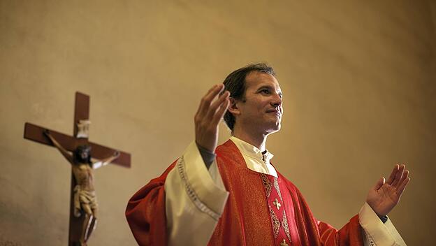Catholic priest on altar praying with open arms during mass service in church model released Symbolfoto PUBLICATIONxINx