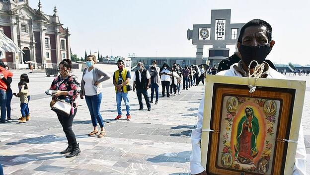 MEXICO CITY, MEXICO - DECEMBER 8: A Faithful holds a picture of the Virgin of Guadalupe while visit the Basilica of Guad