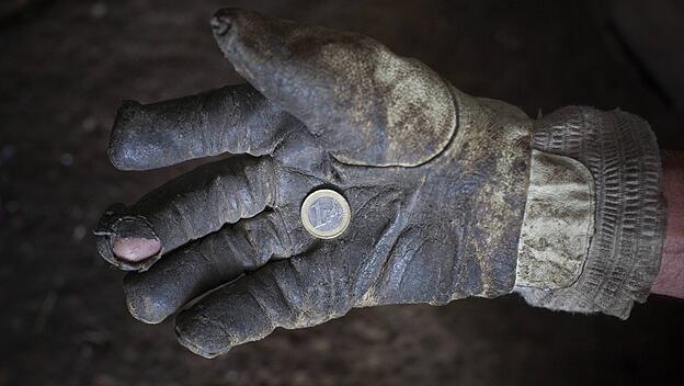 Ein schmutziger Arbeitshandschuh mit einer Ein-Euro-Münze