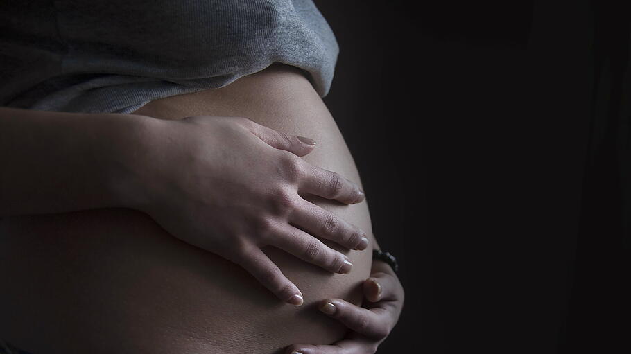 Pregnant woman cradling unborn child