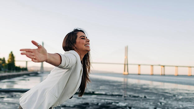 Young woman with open arms standing at riverside model released Symbolfoto DCRF00520