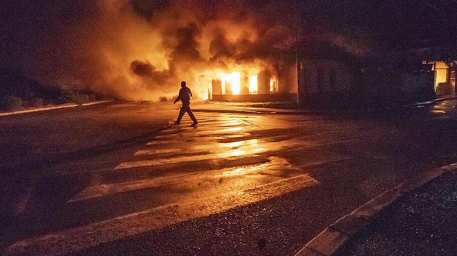 Ein Mann geht nach einem Angriff Aserbaidschans an einem brennendem Gebäude vorbei.