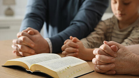 Boy  and  his  godparents  praying  together  at  wooden  table  indoors,  closeup   xkwx adult,  ba