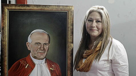 Floribeth Mora vor einem Bild von Papst Johannes Paul II.