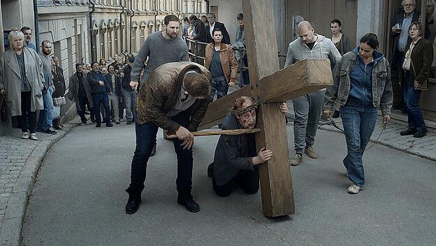 Ein Mann fällt unter dem Kreuz