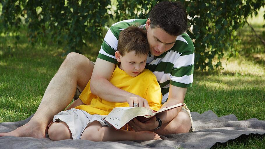 Ein Vater liest mit seinem Sohn in der Bibel