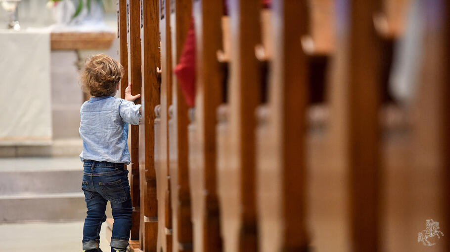 Ein kleines Kind steht im Mittelgang einer Kirche.