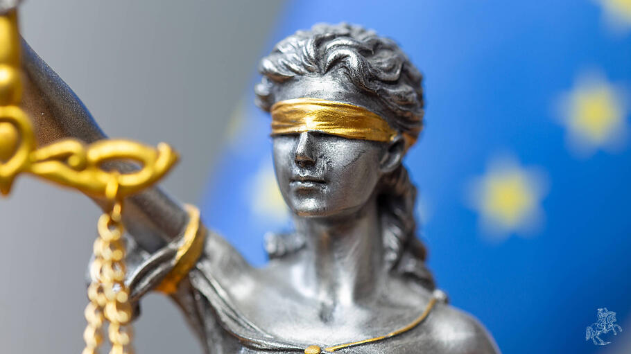 Nahaufnahme einer Justitia vor der Flagge der Europ&auml;ischen Union