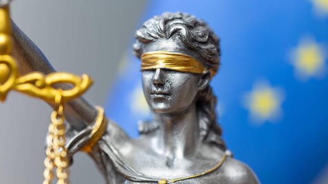 Nahaufnahme einer Justitia vor der Flagge der Europ&auml;ischen Union
