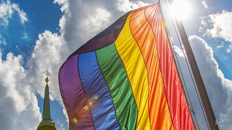 Regenbogenflagge vor Kirchturm