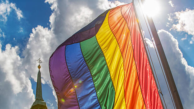 Regenbogenflagge vor Kirchturm