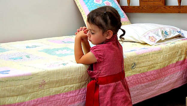 Kind betet an seinem Bett