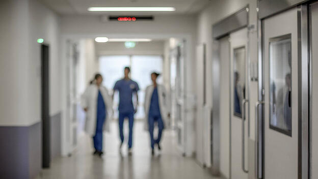 Ärzte, Pflegepersonal im Krankenhausflur entgegenkommend. Themenfoto Zukunft Gesundheitswesen noch unklar Drei ÄrztInnen