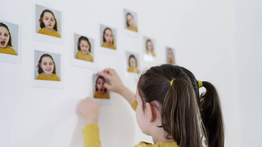 Mädchen klebt Selbstbildnisse an die Wand
