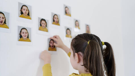 Mädchen klebt Selbstbildnisse an die Wand