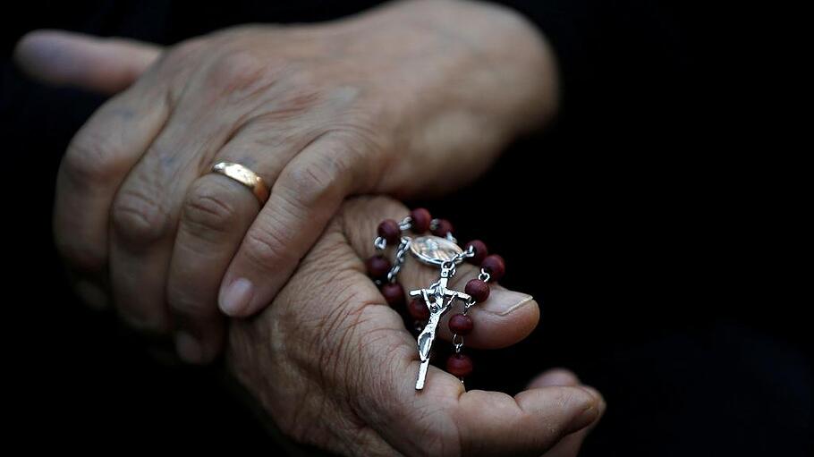An Iraqi Christian woman holds a cross during a prayer session inside the Syriac Orthodox Church of Mart Shmoni during the Good Friday prayers in Erbil