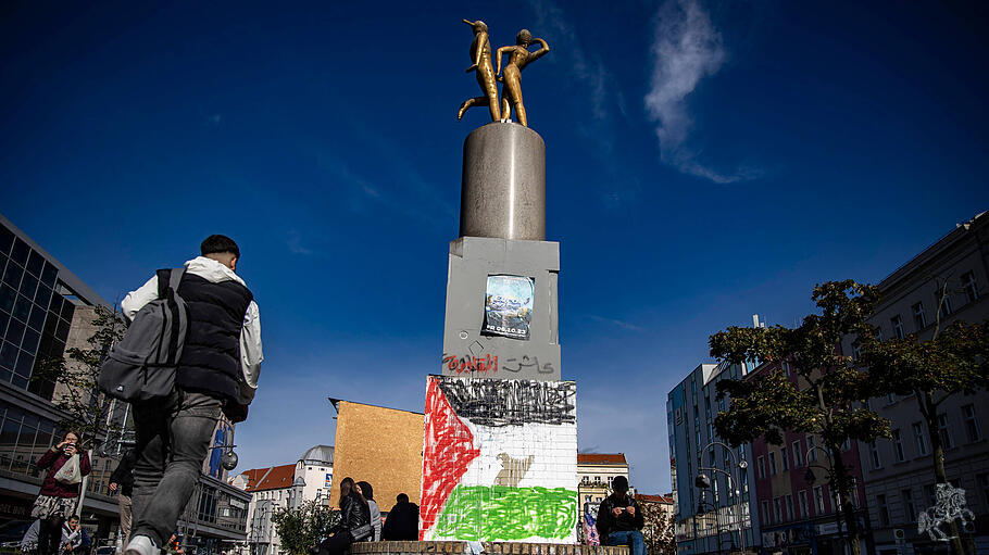 Menschen laufen bei dem Denkmal bemahlt mit der Palaestinensischer Flagge am Herrmannplatz in Berlin Neukoelln am 8. Okt