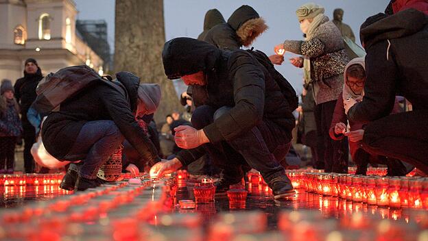 Menschen zünden in Gedenken an die Opfer der Hungersnot von 1932/1933 Kerzen an