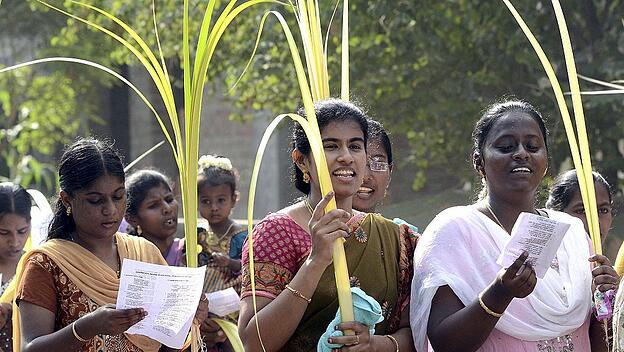 Indian Christian devotees hold palm leaves as they take part in a