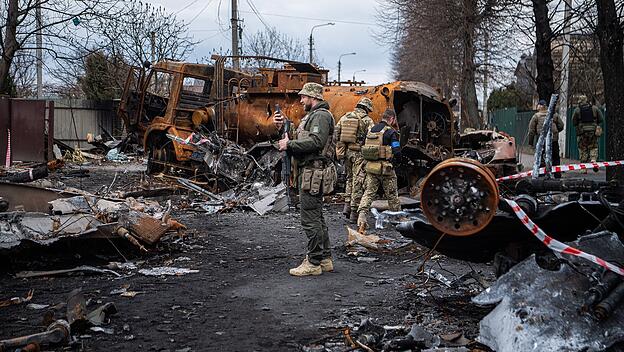 Soldat filmt zerstörte Fahrzeuge und Panzer auf einer Straße in Irpin