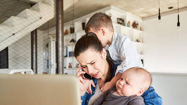 Gestresste Mutter mit Baby und Kind