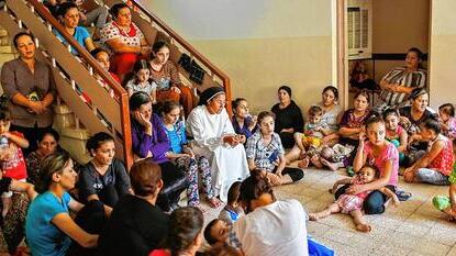 Ordensschwester betet mit aus dem Irak geflohenen Christen