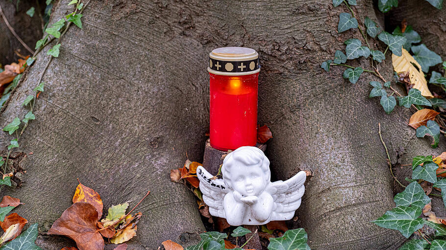 Engelfigur und Grablicht an einem Baum