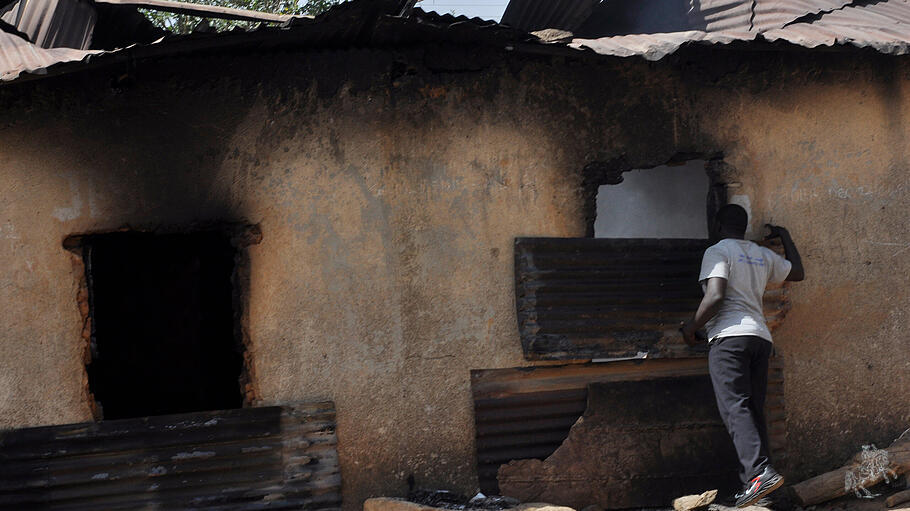 Ein Mann inspiziert ein nach den Terroranschlägen ausgebranntes Haus.