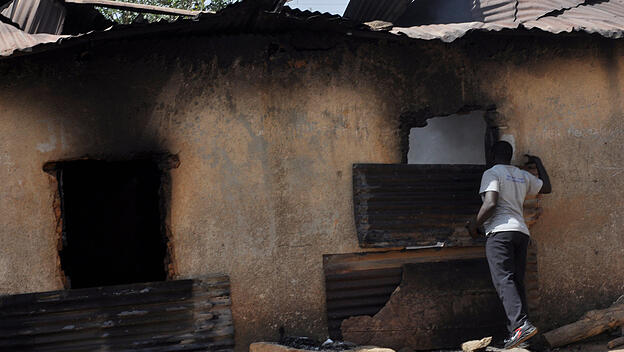 Ein Mann inspiziert ein nach den Terroranschlägen ausgebranntes Haus.