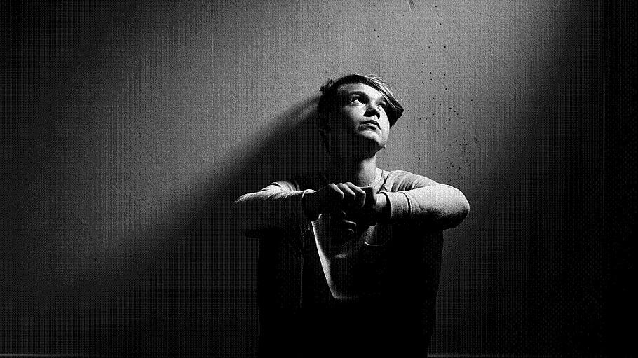 Barefoot thoughtful boy sat against wall in monochome with copy space (jhandersen)