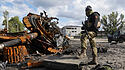 Ukrainischer Soldat steht neben einem zerstörten russischen Panzer