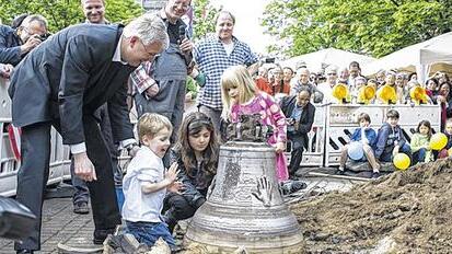 Pfarrer Neukirchen bestaunt mit einigen Kindern die Friedensglocke