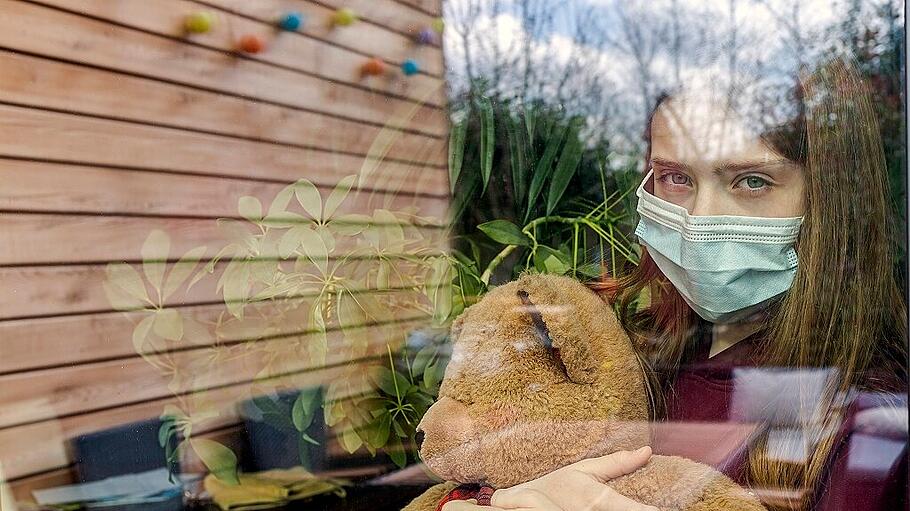 Portrait of girl with surgical mask and teddy bear behind window pane model released Symbolfoto property released SARF0