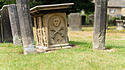 Ein alter Grabstein auf einem englischen Friedhof zeigt Schädel und Knochen als Symbole für den Tod.