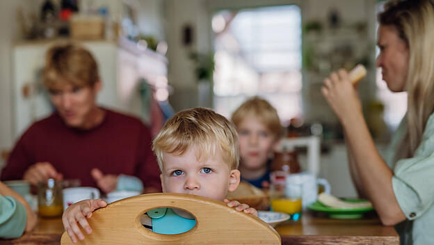Family eating breakfast together in home kitchen. Healthy breakfast or snack before school and work. Mother helping youn